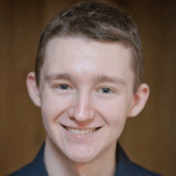 A man wearing a grey collar shirt with short brown hair smiling.
