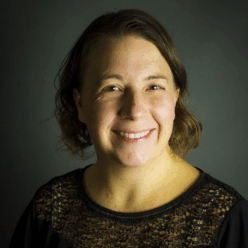 A woman wearing a black shirt with short brown hair smiling.