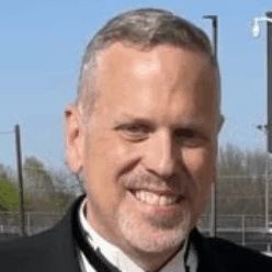 A man wearing a black suite smiling.